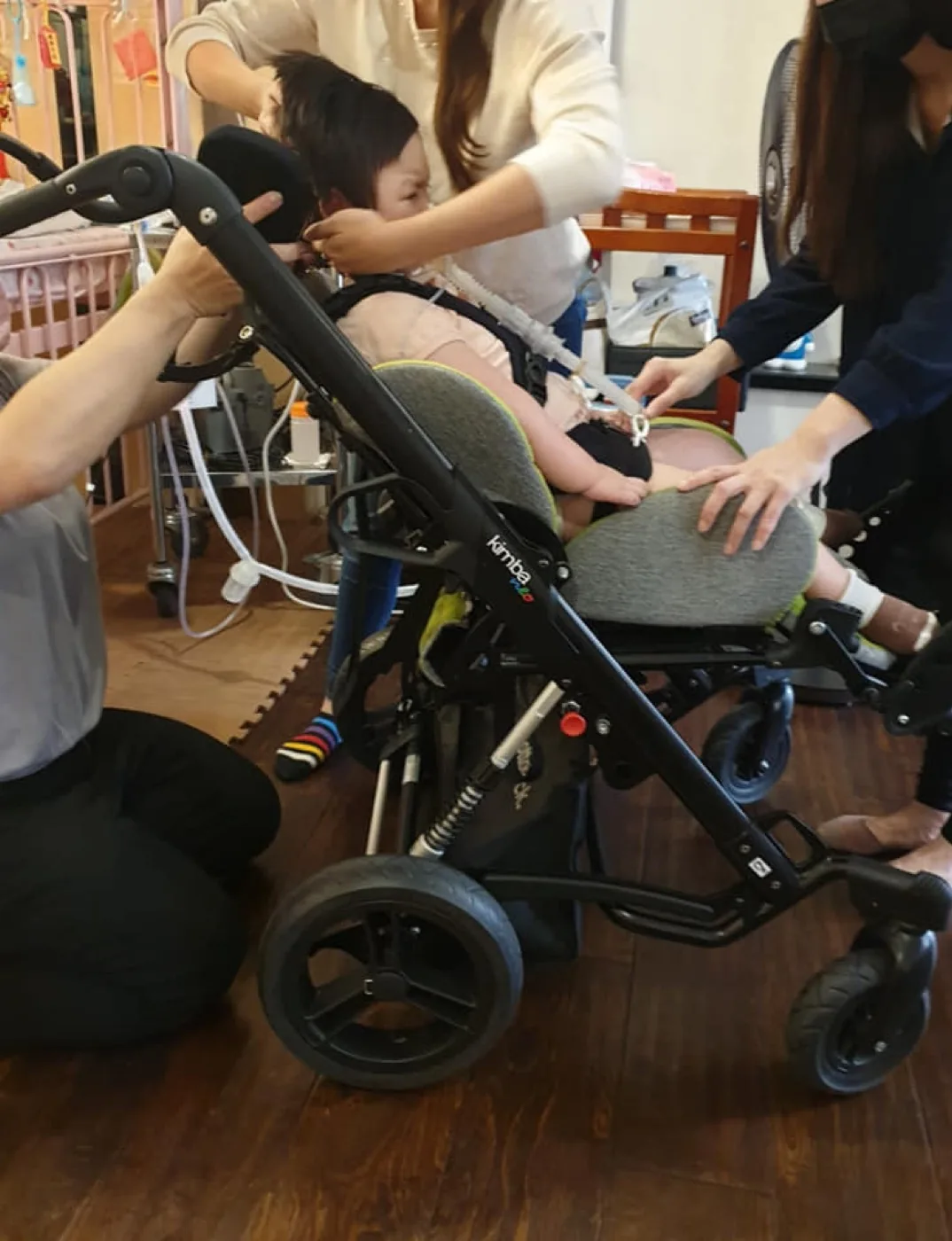 孩子坐在特製擺位推車上，展現居家輔具協助氣切兒童外出的樣子。